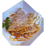 Crepe with Caramelized cinnamon apple and whipped cream on a white plat.