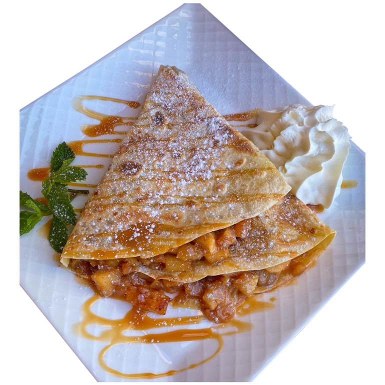 Crepe with Caramelized cinnamon apple and whipped cream on a white plat.