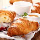 Croissants and cups of honey on a white cloth on a table. Croissant are perfect breakfast at Fraise Cafe in Fullerton, CA.