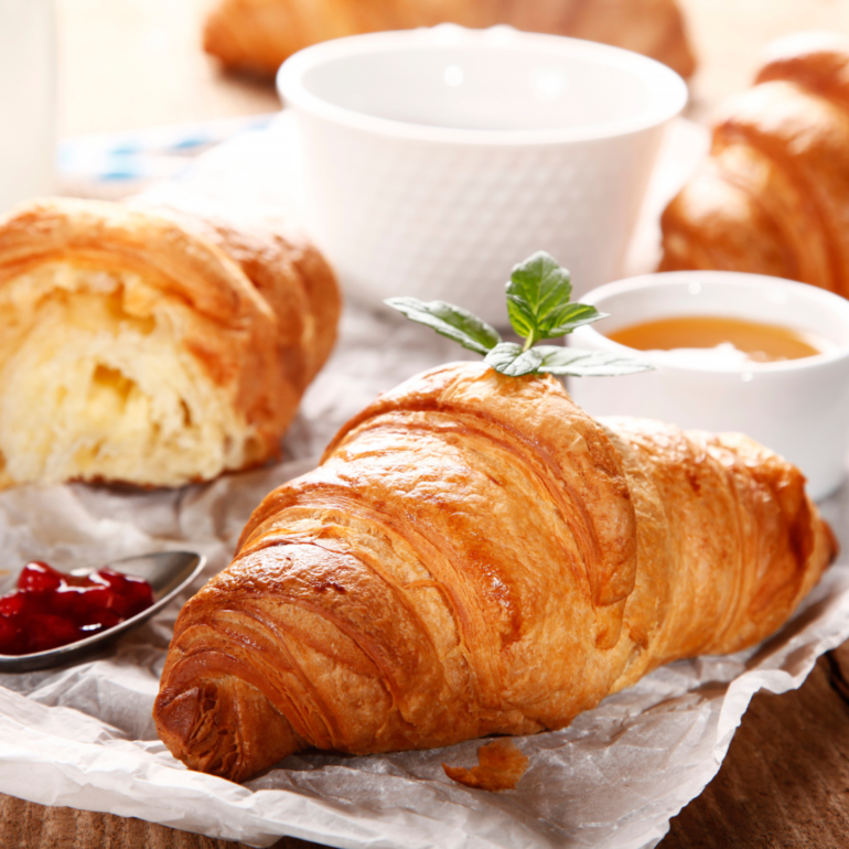 Croissants and cups of honey on a white cloth on a table. Croissant are perfect breakfast at Fraise Cafe in Fullerton, CA.