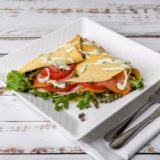 Norwegian Crepe, made with Nordic Smoked Salmon, topped with spring lettuce mix, ripe tomatoes, red onions, enticing capers, and our Dill & Chives Sauce the Most delicious seafood crepe in Orange County California.