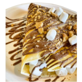 A crepe covered with chocolate graham crackers marshmallows on a plate.