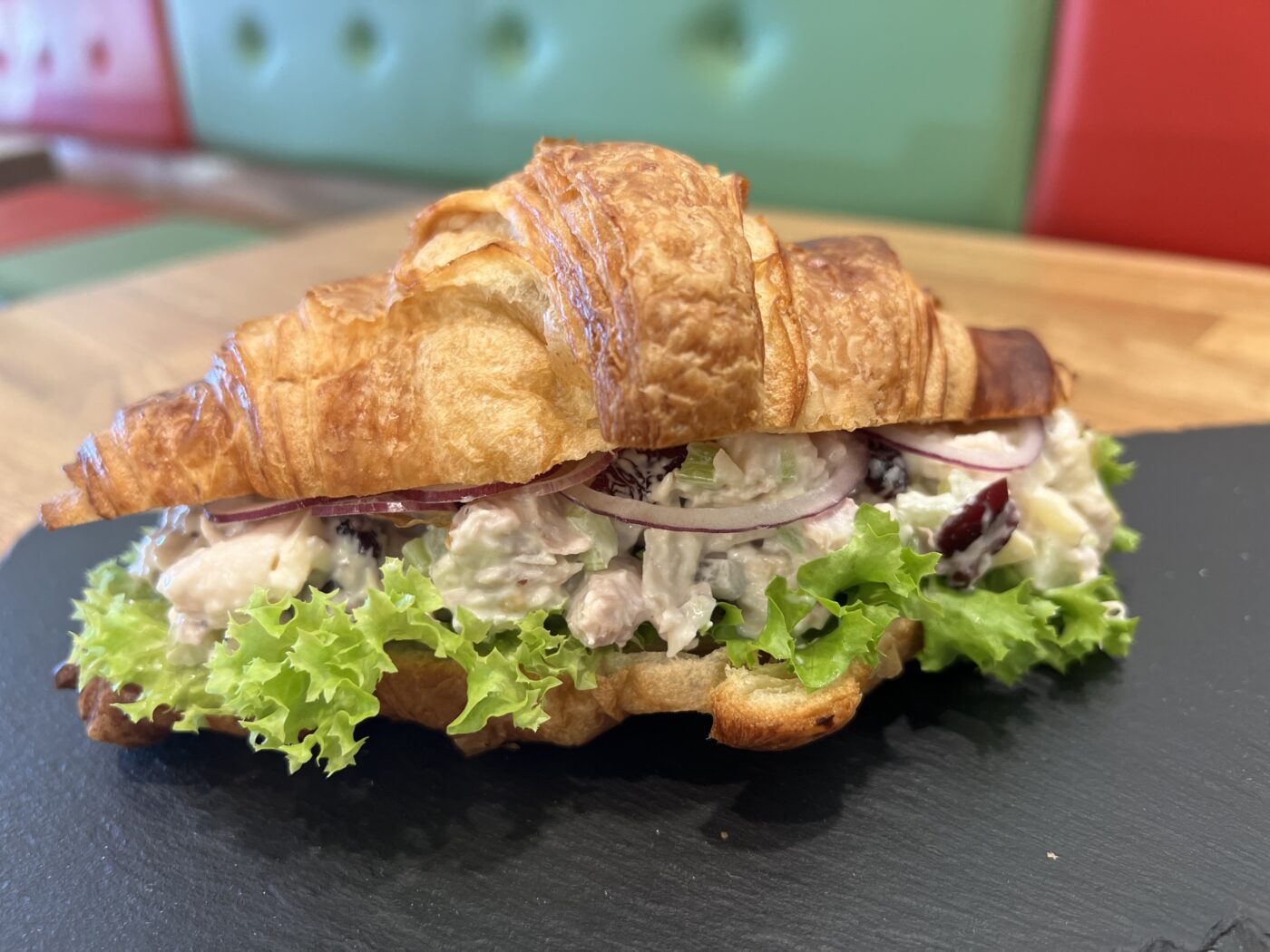 Chicken Salad in a Croissant with lettuce, with Fraise Cafe benches in the background