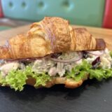 Chicken Salad in a Croissant with lettuce, with Fraise Cafe benches in the background